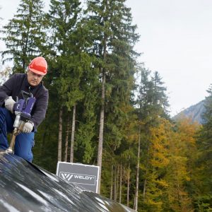 Técnico utilizando extrusora manual Weldy Booster EX3 para soldar geomembrana de polietileno em obra ao ar livre.