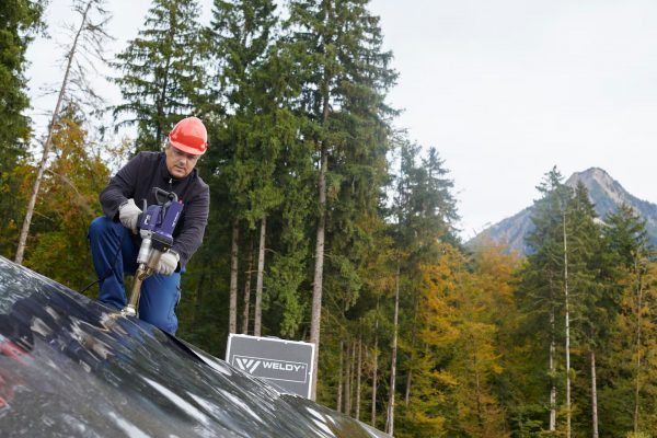 Técnico utilizando extrusora manual Weldy Booster EX3 para soldar geomembrana de polietileno em obra ao ar livre.