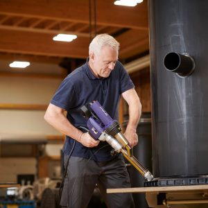 Técnico utilizando a extrusora manual Weldy Booster EX3 para soldar reservatório plástico em ambiente industrial.