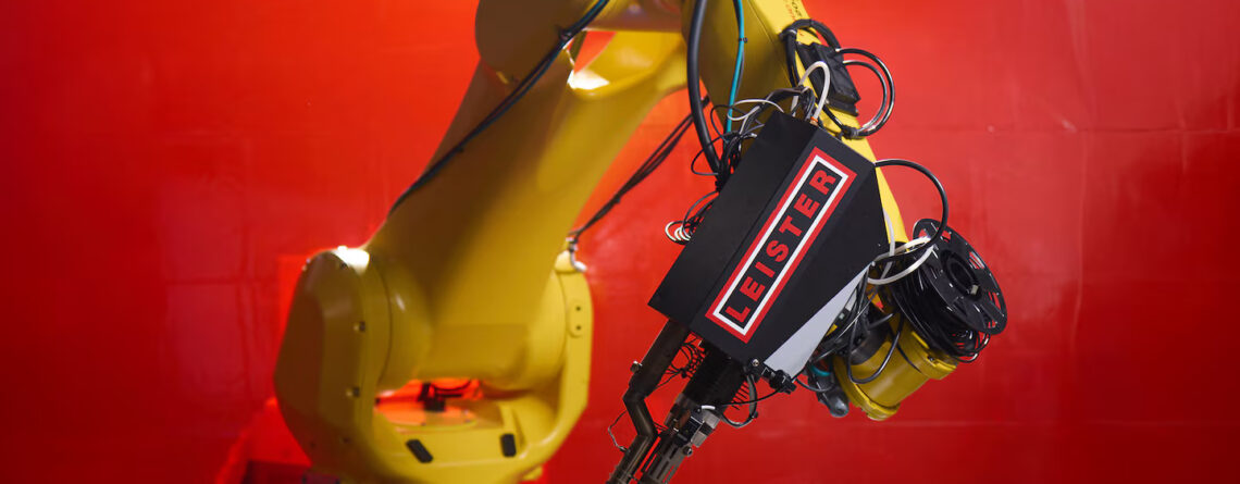 Braço robótico FANUC equipado com extrusora Leister WELDPLAST 200-i, realizando soldagem plástica de alta precisão