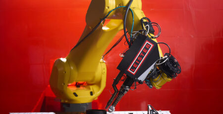 Braço robótico FANUC equipado com extrusora Leister WELDPLAST 200-i, realizando soldagem plástica de alta precisão