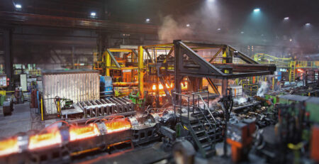 Usina siderúrgica com máquinas em operação, mostrando o ambiente desafiador onde os sistemas de secagem Leister ajudam a manter a confiabilidade elétrica
