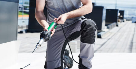 Técnico realizando soldagem de manta sintética em cobertura com ferramenta de ar quente Leister TRIAC, aplicada em serviços de manutenção e impermeabilização de telhados