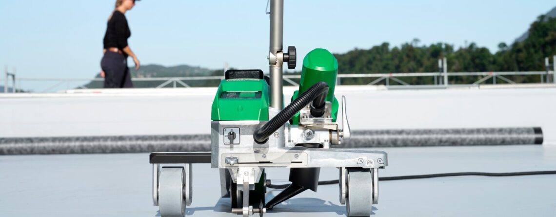 soldadora automática Leister VARIMAT 500 realizando soldagem contínua de membrana termoplástica em telhado comercial, assegurando desempenho consistente e alta eficiência operacional
